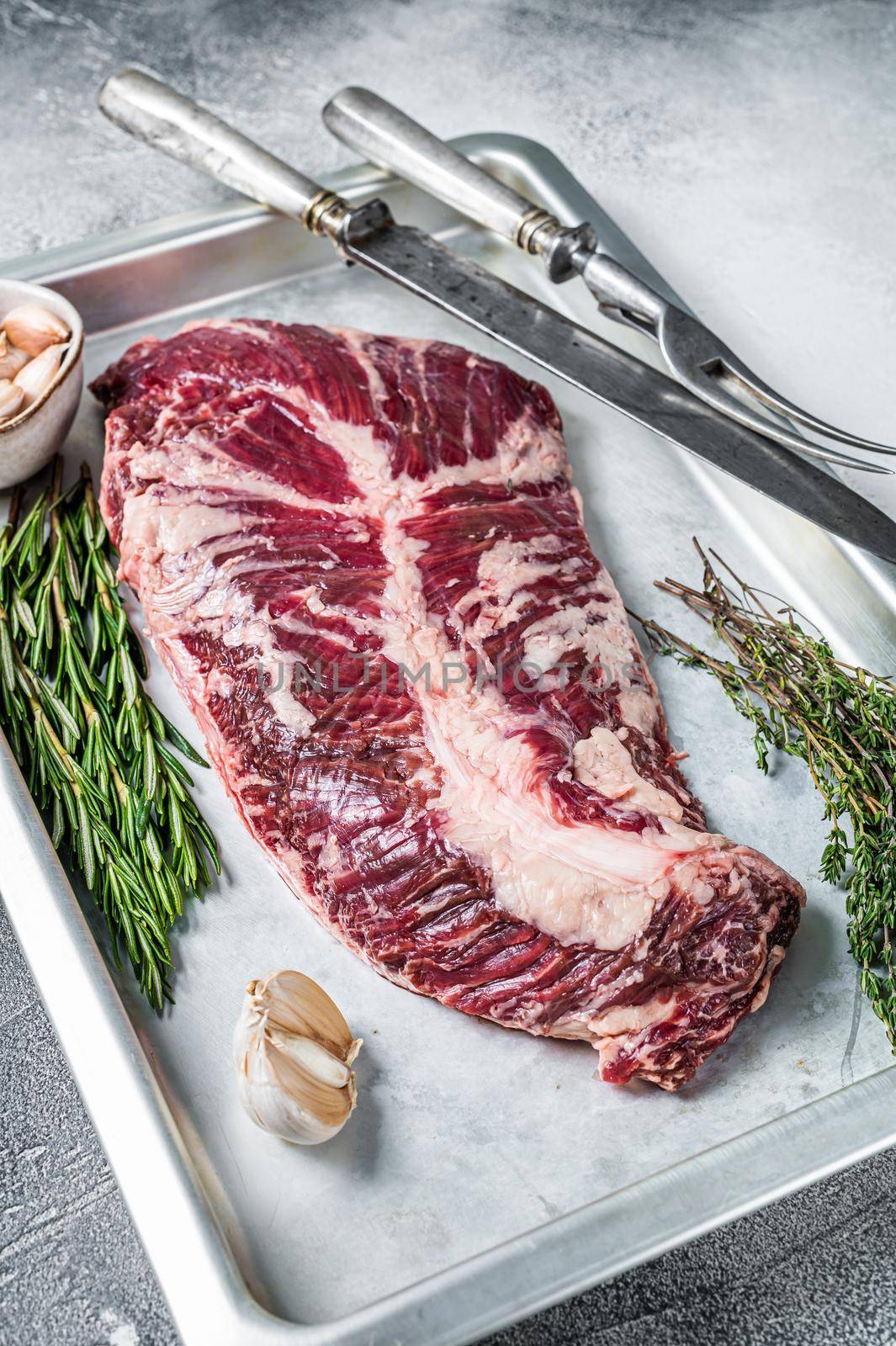 Raw hanger or onglet beef meat steak in steel tray with herbs. White background. Top View.