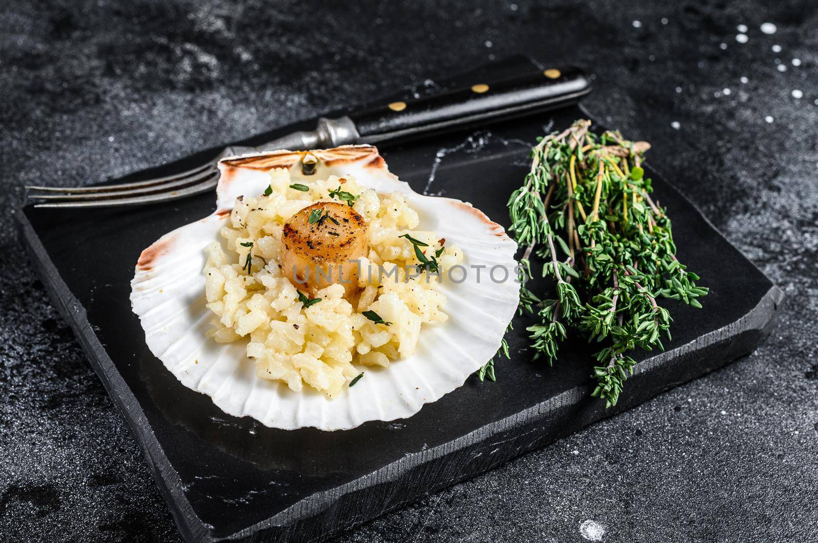 Risotto with pan seared sea scallops in a shell. Black background. Top view by Composter