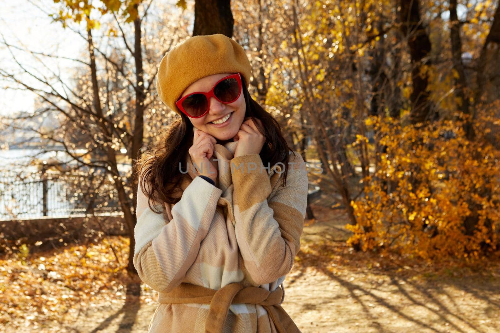 Seasonal autumn fashion. Modern young woman wearing fashionable warm clothes posing in the autumn park