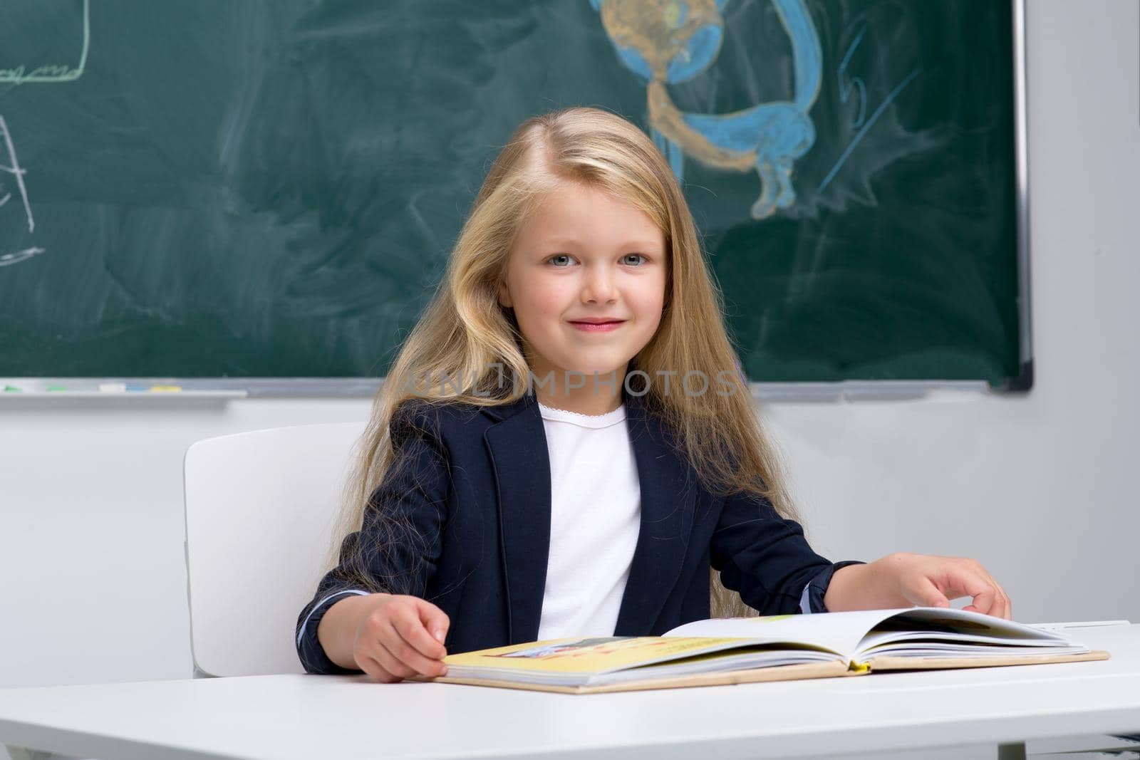 Happy schoolgirl sitting at desk by kolesnikov_studio