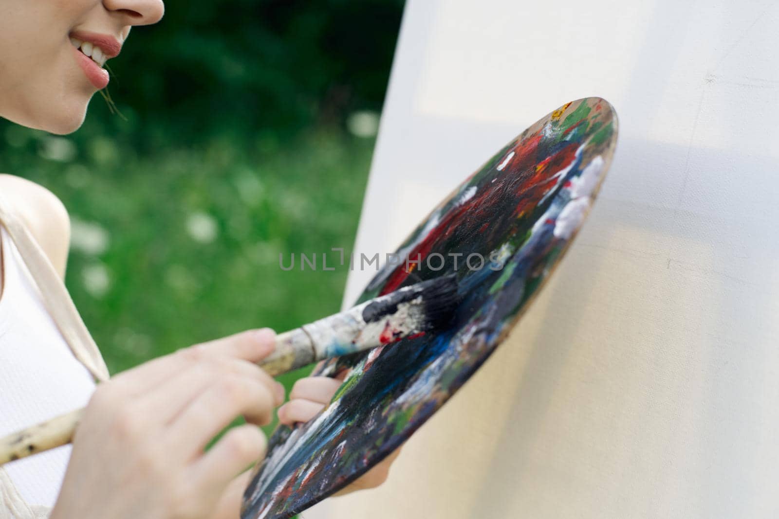 woman artist in white dress paint palette drawing close-up. High quality photo