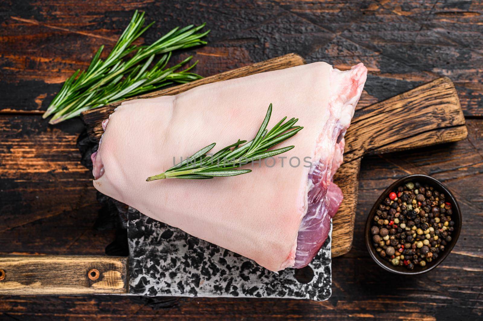 Raw pork Eisbein knuckle ham on a wooden board with meat cleaver. Dark Wooden background. Top view by Composter