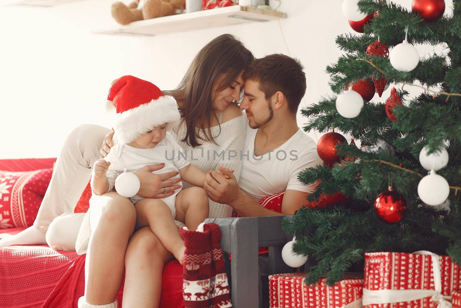 Mother in a white sweater. Family with christmas gifts. Child with parents in a christmas decorations.