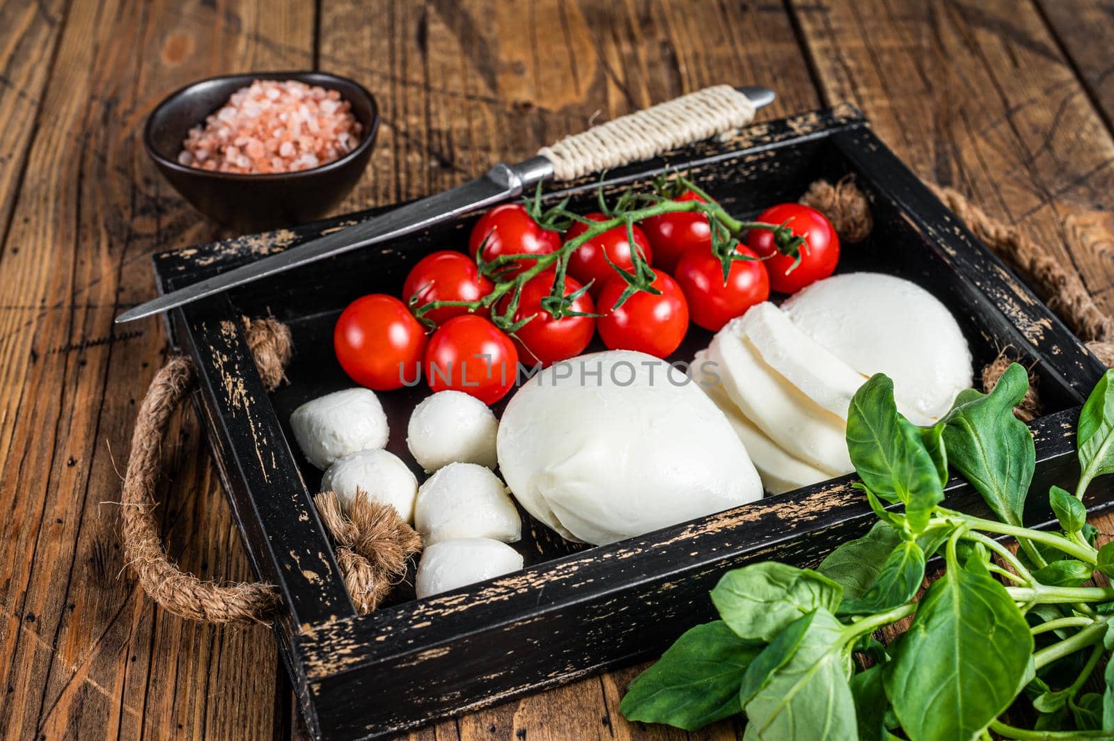 Mozzarella cheese, basil and tomato cherry in wooden tray, Caprese salad. wooden background. Top view by Composter