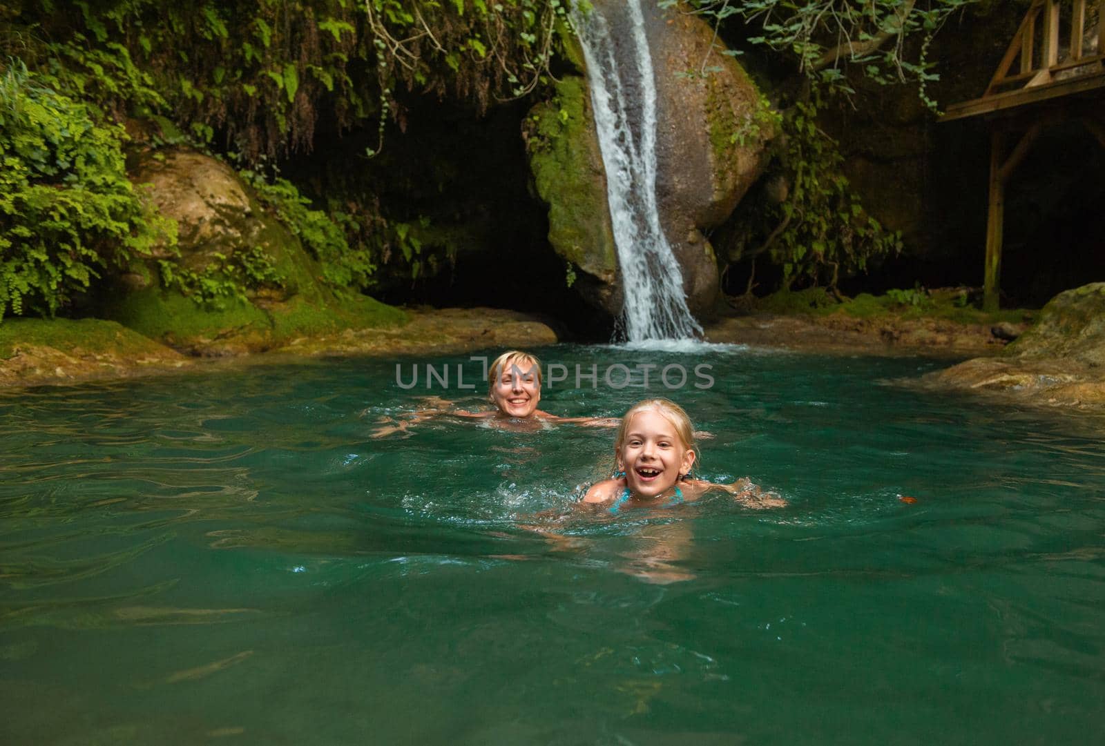 Mom and daughter at a waterfall in the jungle. Travel in nature near a beautiful waterfall, Turkey