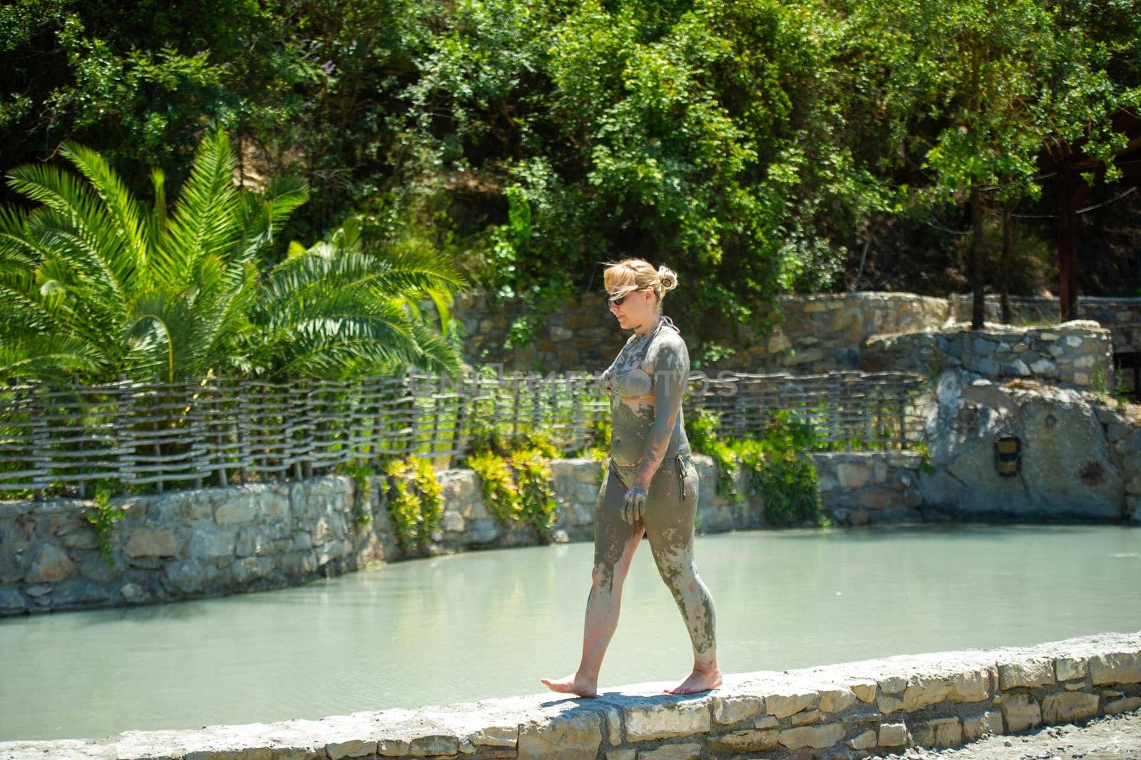 A girl walks along a pool with mud baths at a resort in Turkey.Health improvement in therapeutic mud