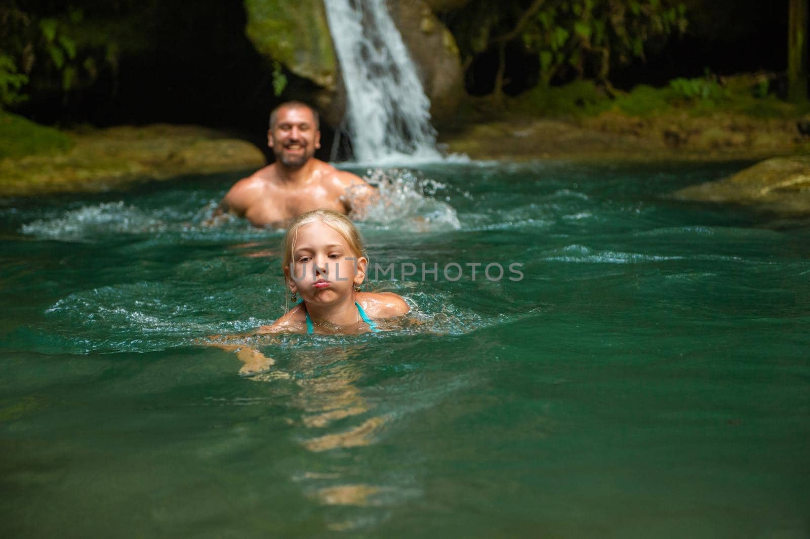 Father and daughter at a waterfall in the jungle. Traveling in nature near a beautiful waterfall, Turkey.