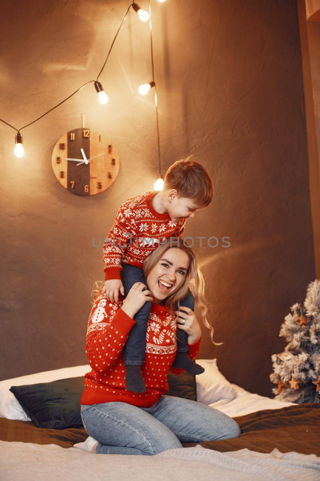 Beautiful mother with child. Family in cristmas atmosphere. Little boy on a bed.
