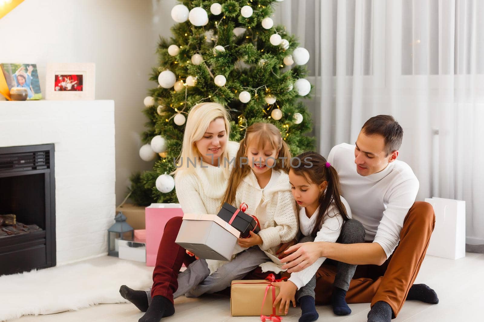 Happy family playing with Christmas gifts at home by Andelov13