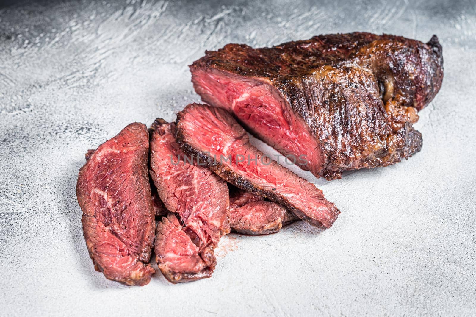 Roasted hanger or Onglet sliced beef meat steak on a table. White background. Top View.