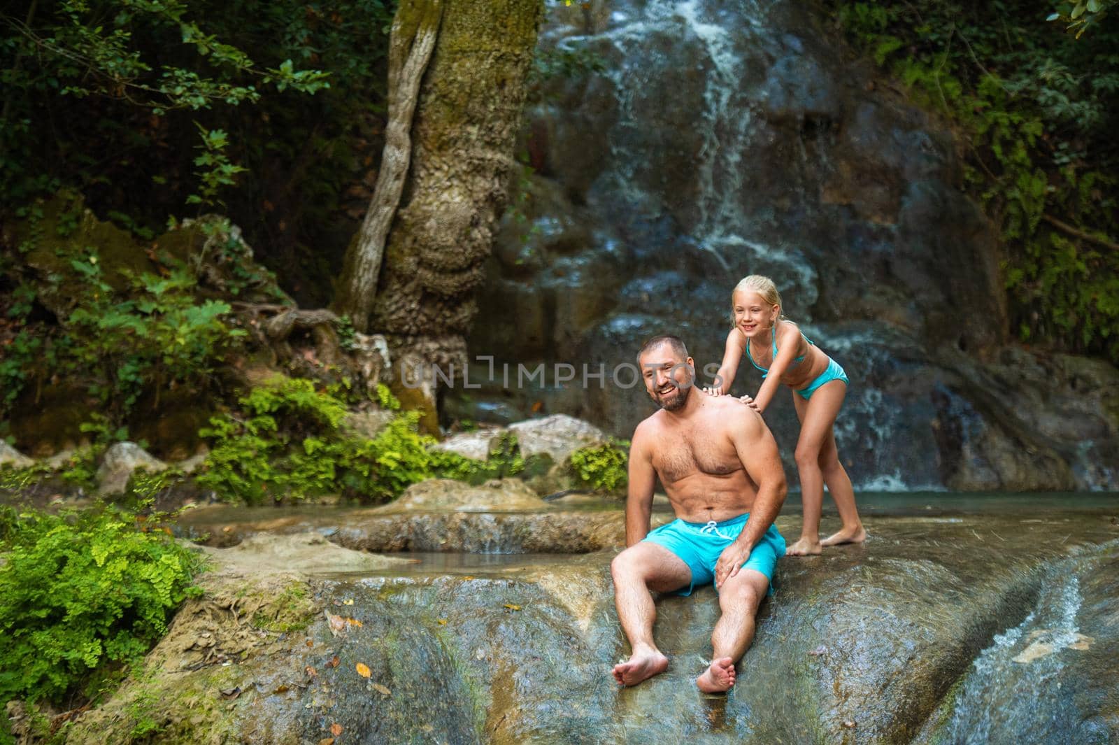 Father and daughter at a waterfall in the jungle. Traveling in nature near a beautiful waterfall, Turkey.