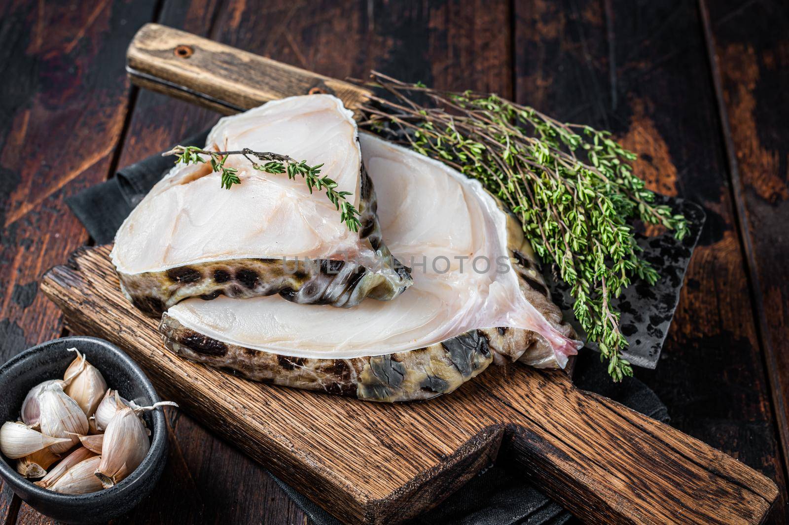 Fresh Raw wolffish o wolf fish Steak on a butcher board. Dark wooden background. Top view by Composter