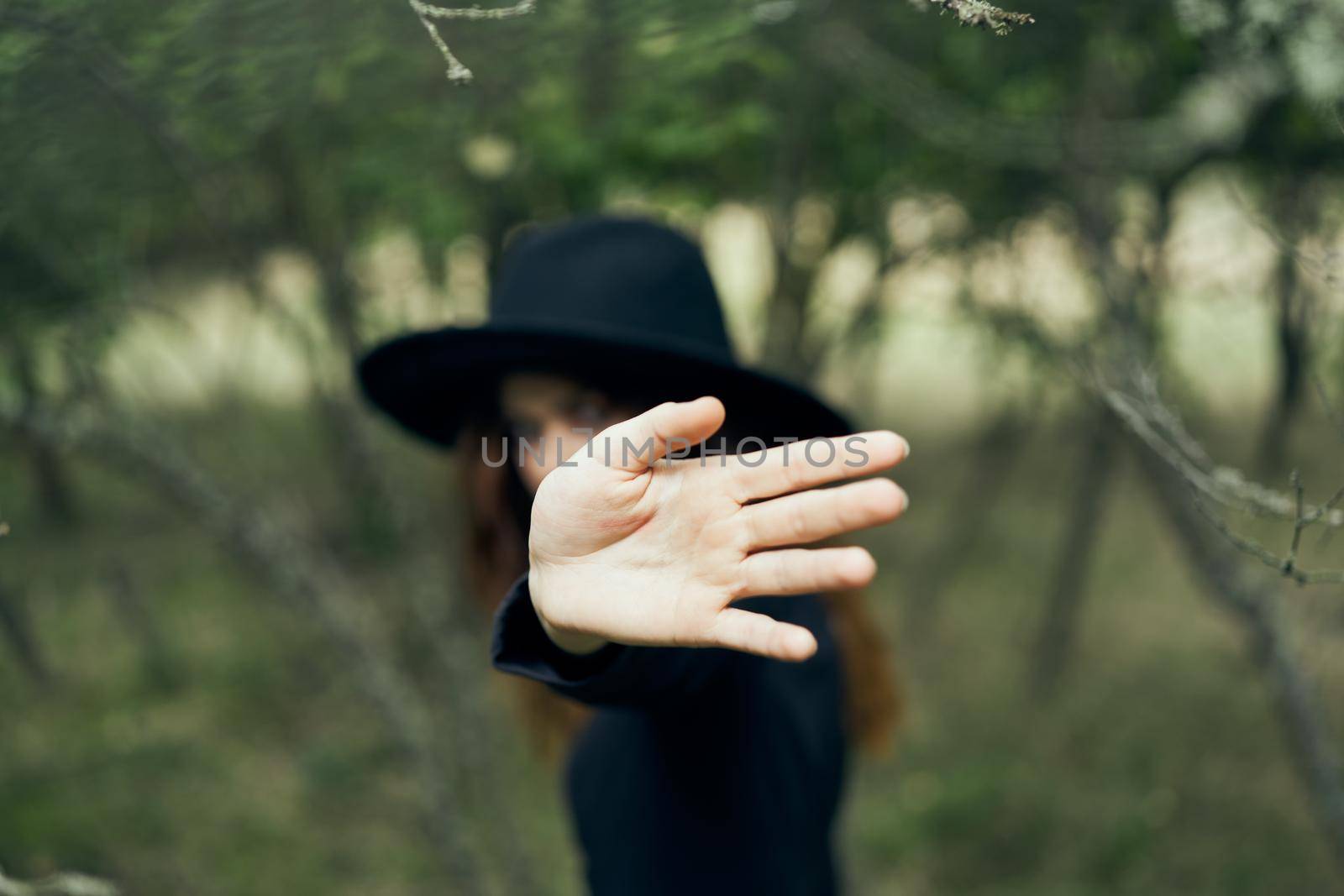 woman in a black hat gesturing with her hands witch magic fantasy. High quality photo