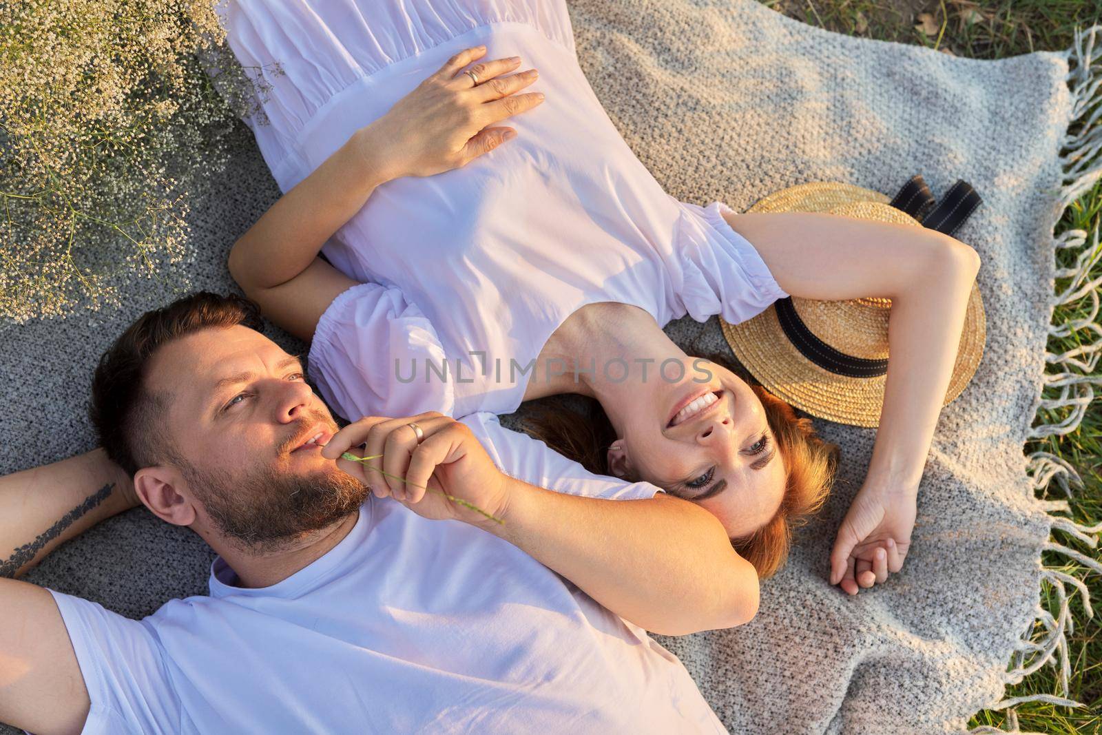 Happy romantic middle aged couple, top view on smiling faces lying on blanket, in sunny sunset light. Love, relationships, date, family, lifestyle, people 30s 40s age concept