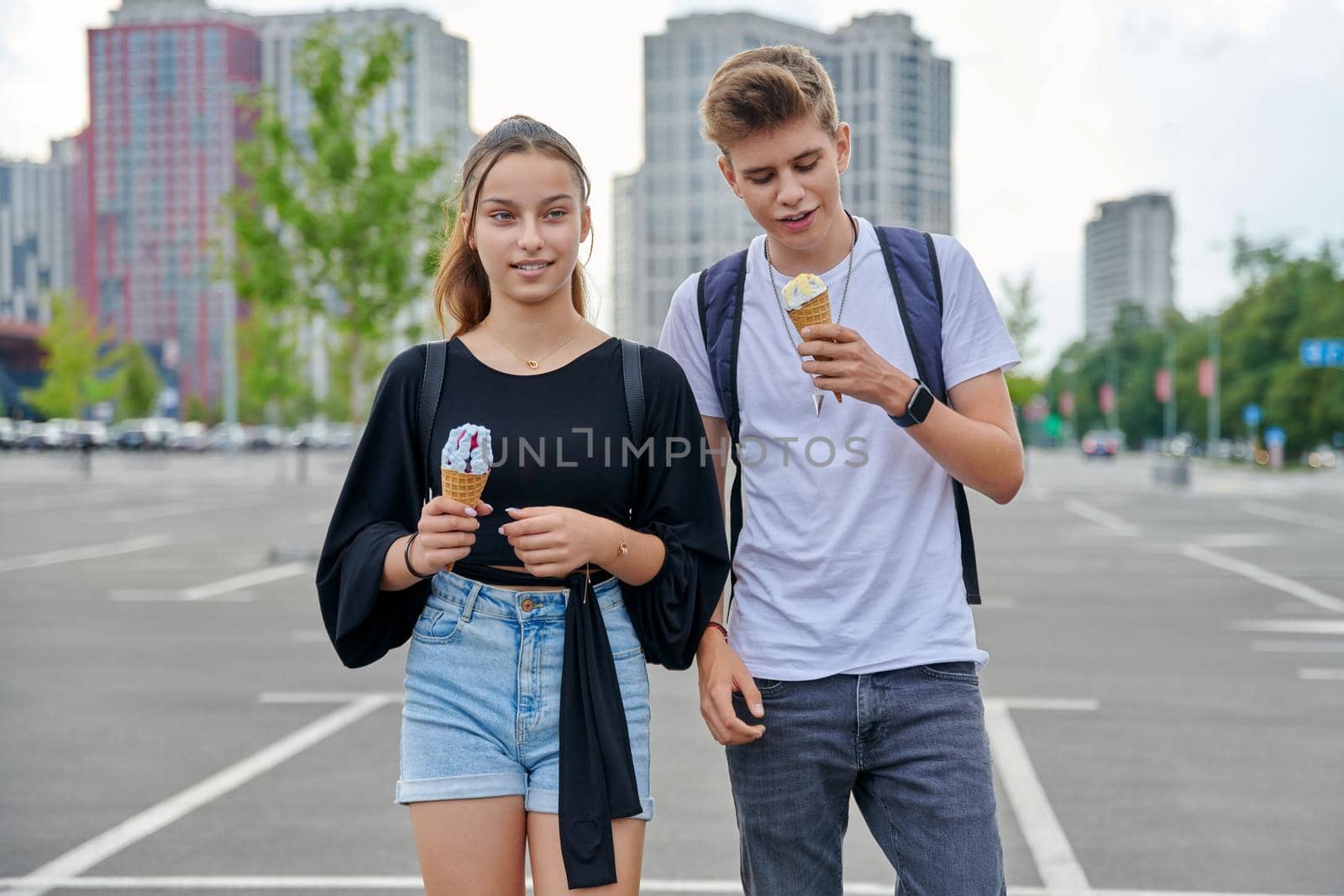Happy talking couple of teenagers walking together in city, guy and teenage girl with ice cream, friendship, relationship, summer, leisure, lifestyle, adolescence concept
