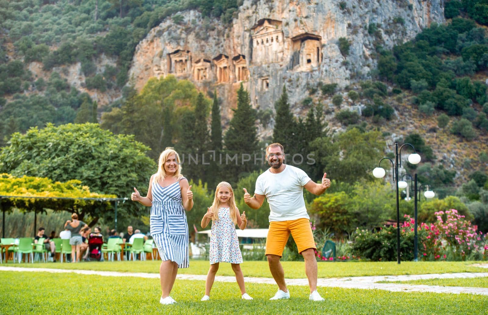 A happy family stands on the background of a mountain in the city of Dalyan.People near Lycian tombs in Turkey.