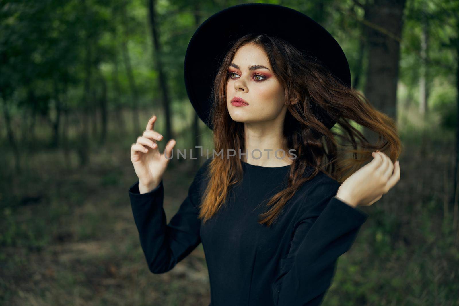 woman witch in black hat in the forest posing fantasy. High quality photo