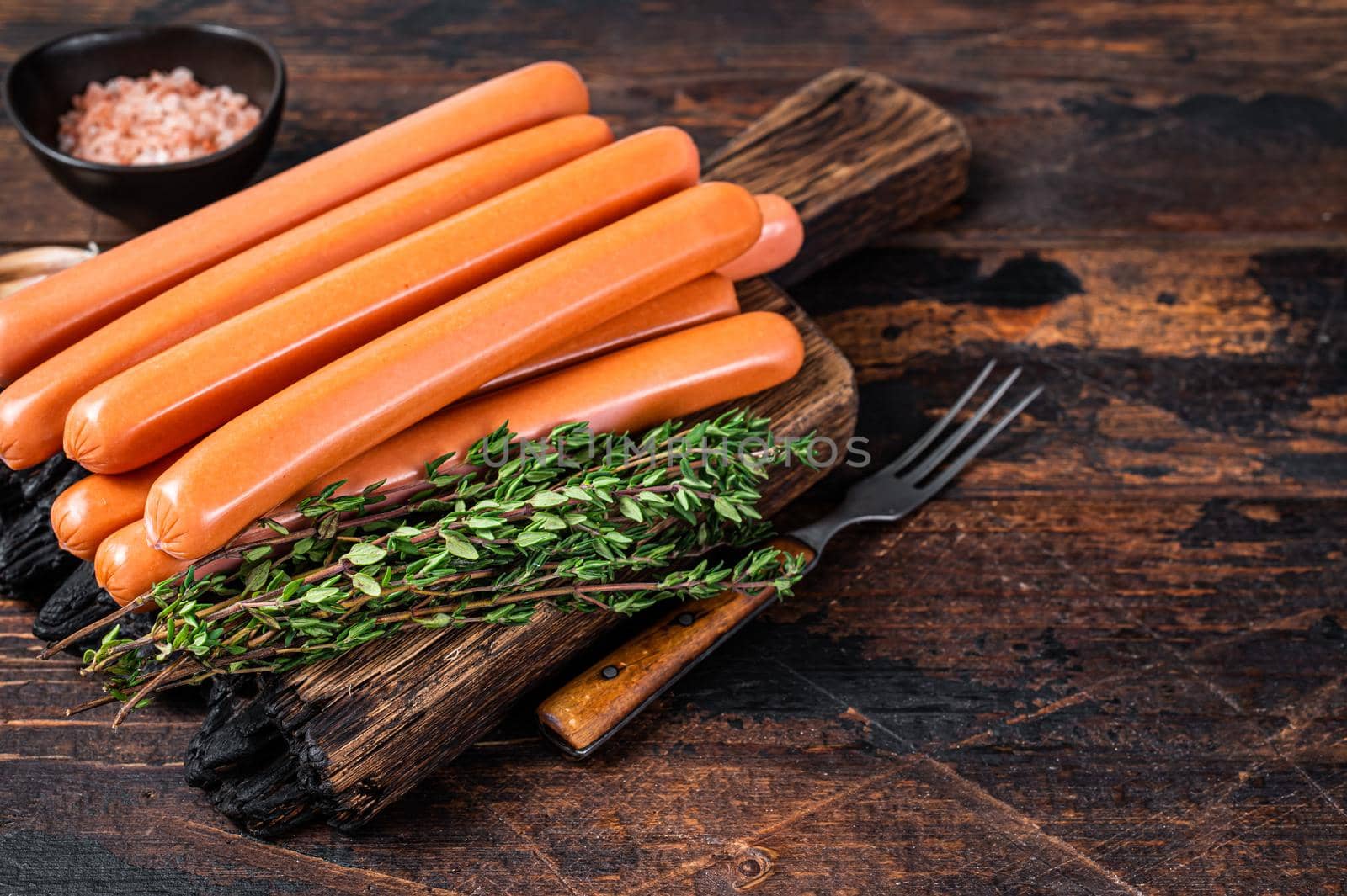 Frankfurter sausages on wooden cutting board. Dark Wooden background. Top view. Copy space.