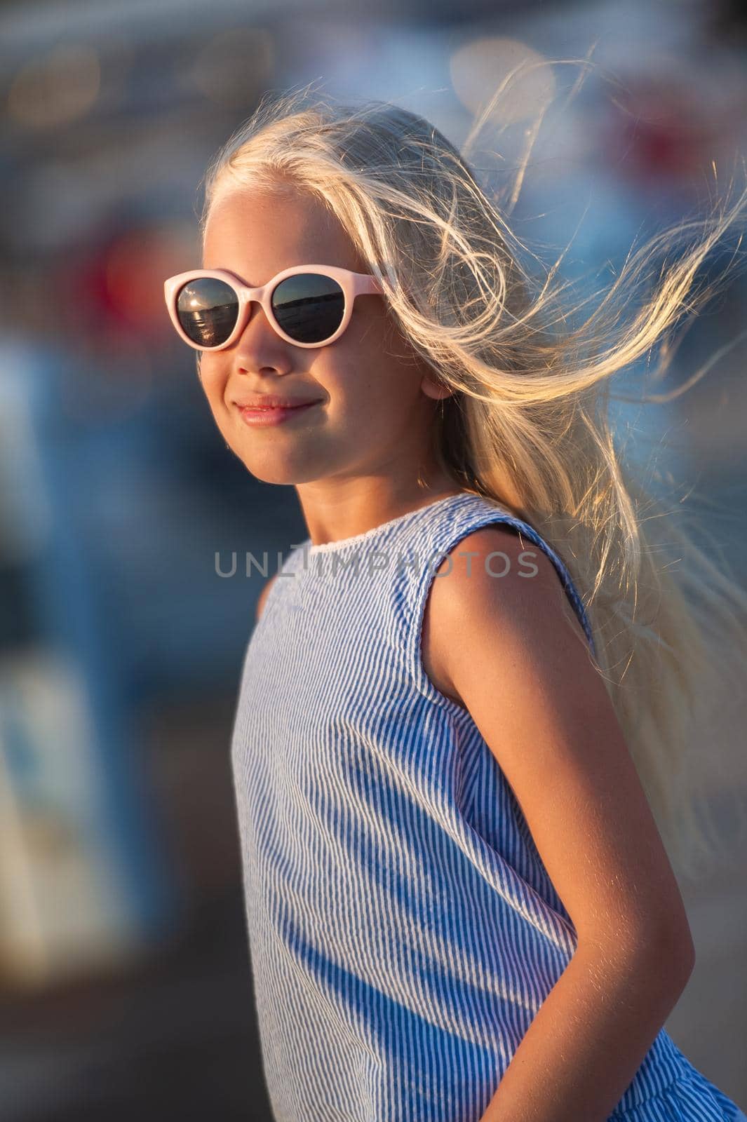 Portrait of a cute smiling little girl with glasses.A girl in shorts and a blue T-shirt at sunset by the sea.Turkey.