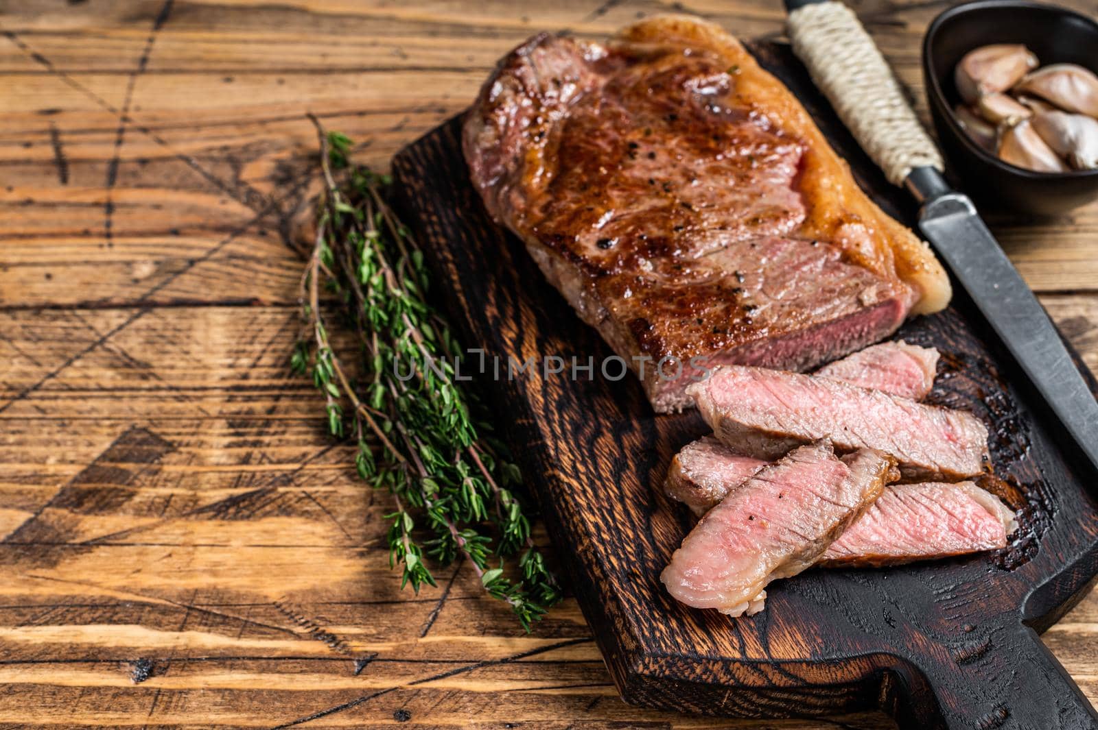 Sliced Grilled new york strip beef meat steak or striploin on a wooden board. background. Top view. Copy space by Composter