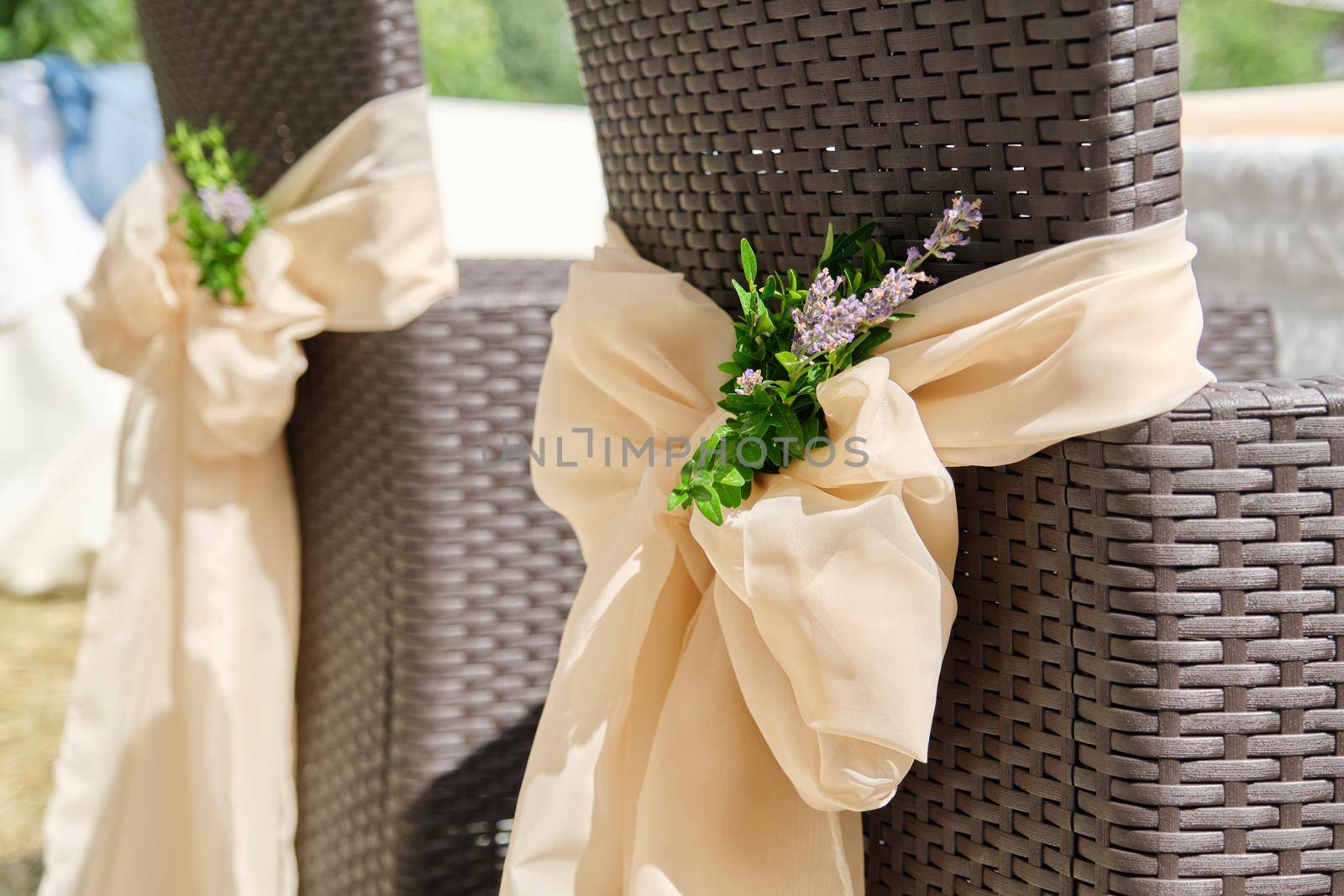 Close-up of rattan garden chairs decorated with textiles with flowers for a party, ceremony by VH-studio