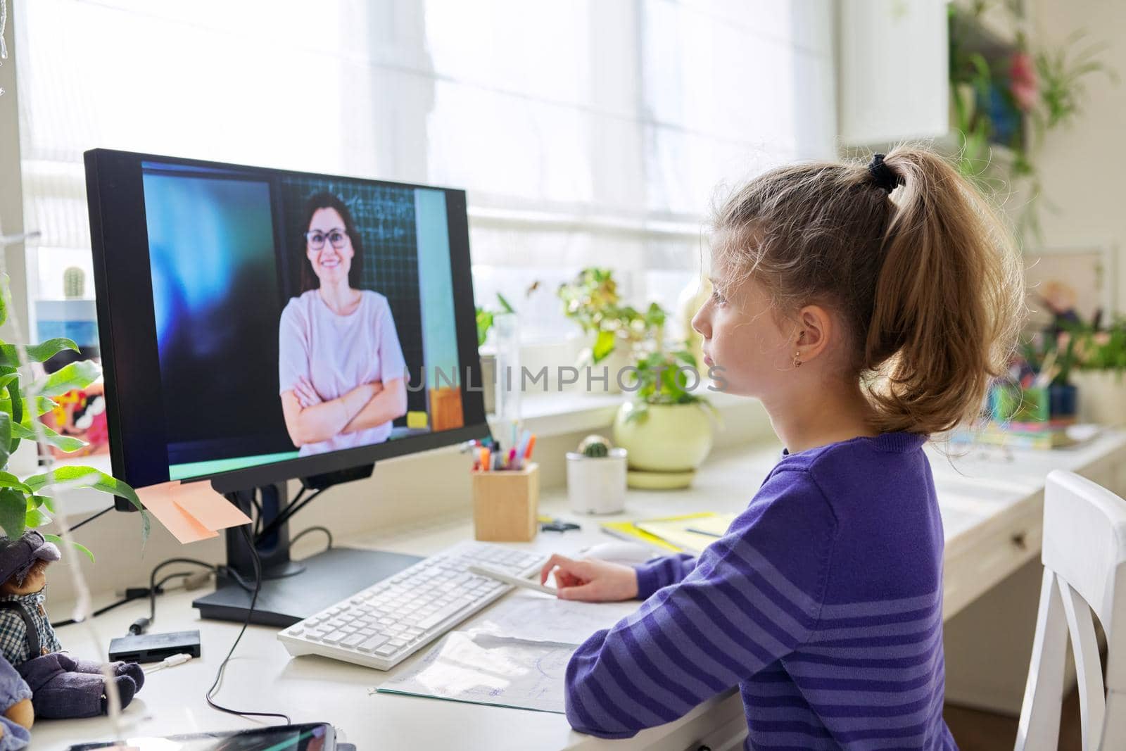 Child preteen girl studying at home using video lesson on computer. Online learning, remote lessons, e-education, technologies in education