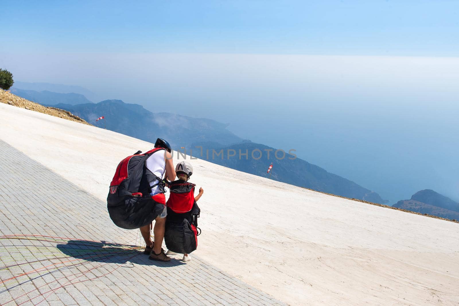 A little girl with an instructor in paragliding gear is preparing for a flight from Mount Babadag.Turkey.