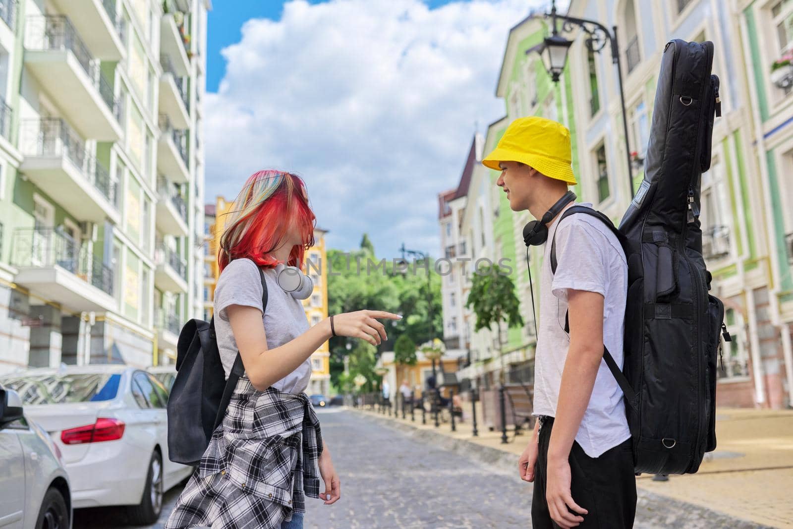 Creative fashionable youth. Talking guy with guitar in case and beautiful girl with trendy dyed colored hair, city street background