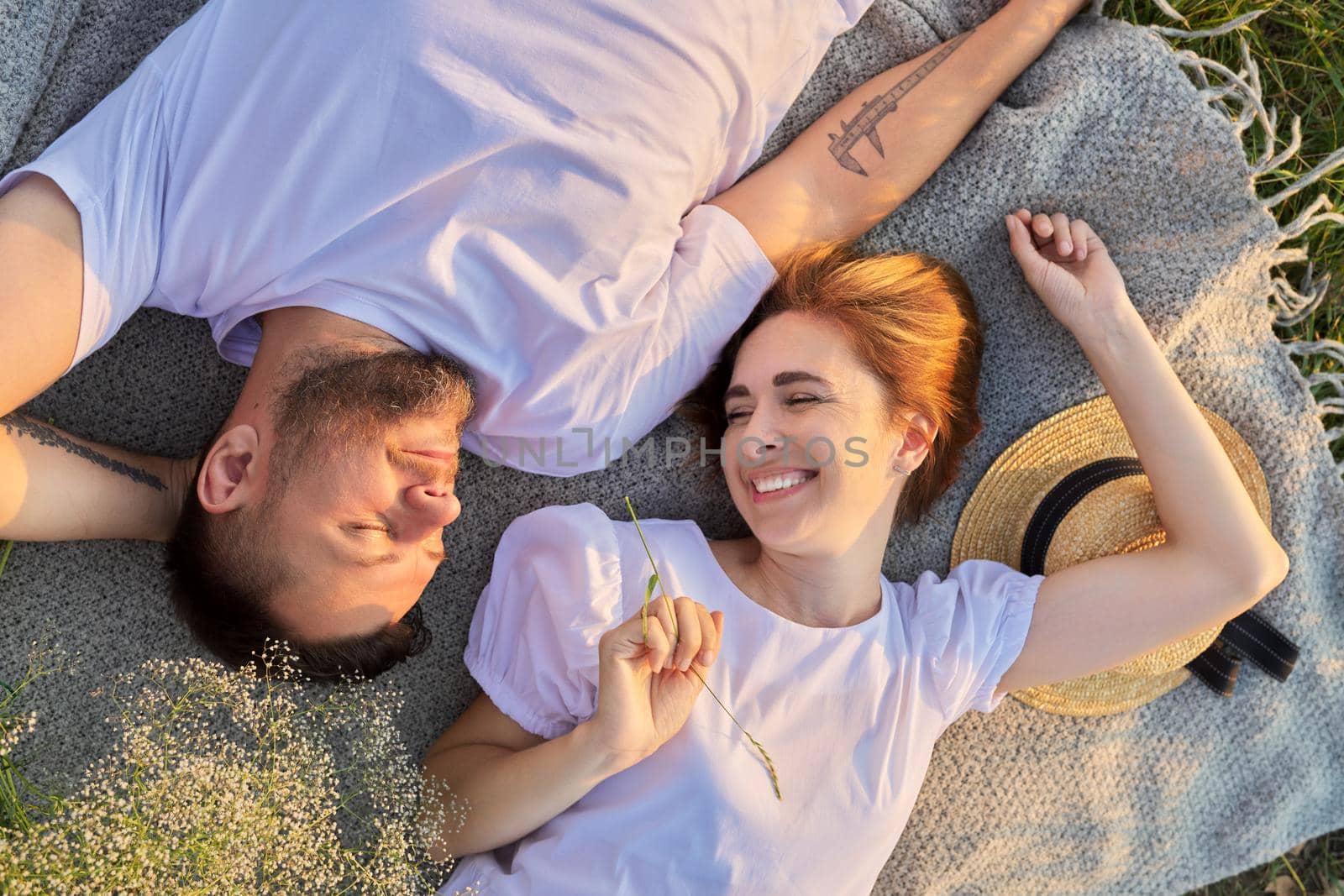 Portrait of beautiful happy couple in 30s 40s. Top view of smiling faces of man and woman lying together in sunset sunlight. Middle-aged people in love, relationship, relaxation, happiness, lifestyle