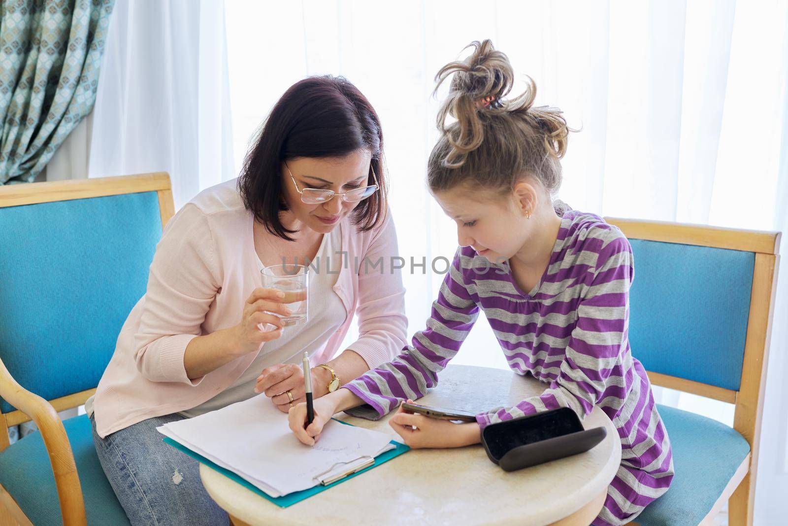 Preteen child girl at meeting with therapist, social worker, counselor in office, kid showing his smartphone to teacher. Psychology, education, therapy, mental health, children concept