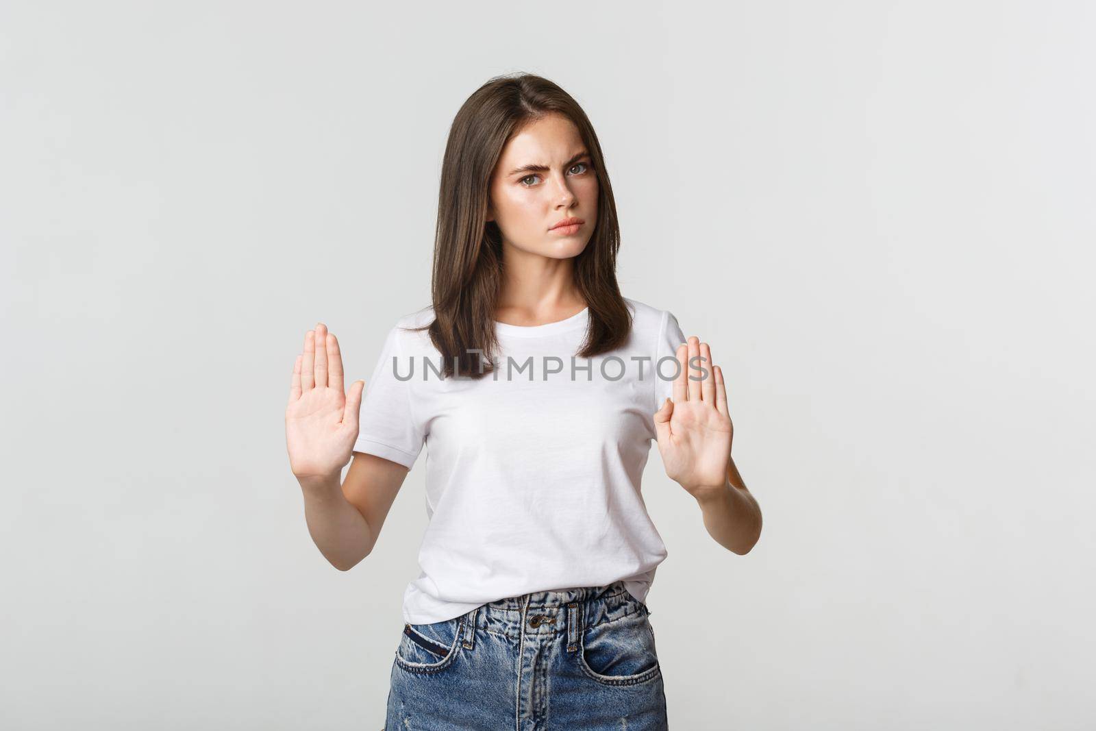 Serious displeased young woman showing stop gesture, saying no.