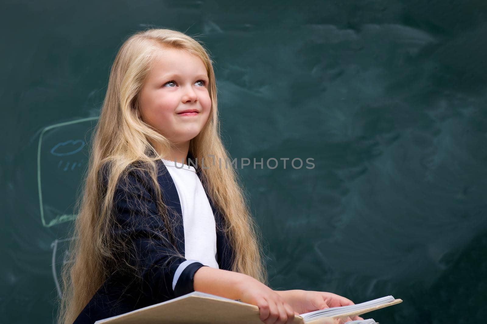 Happy schoolgirl sitting at desk by kolesnikov_studio
