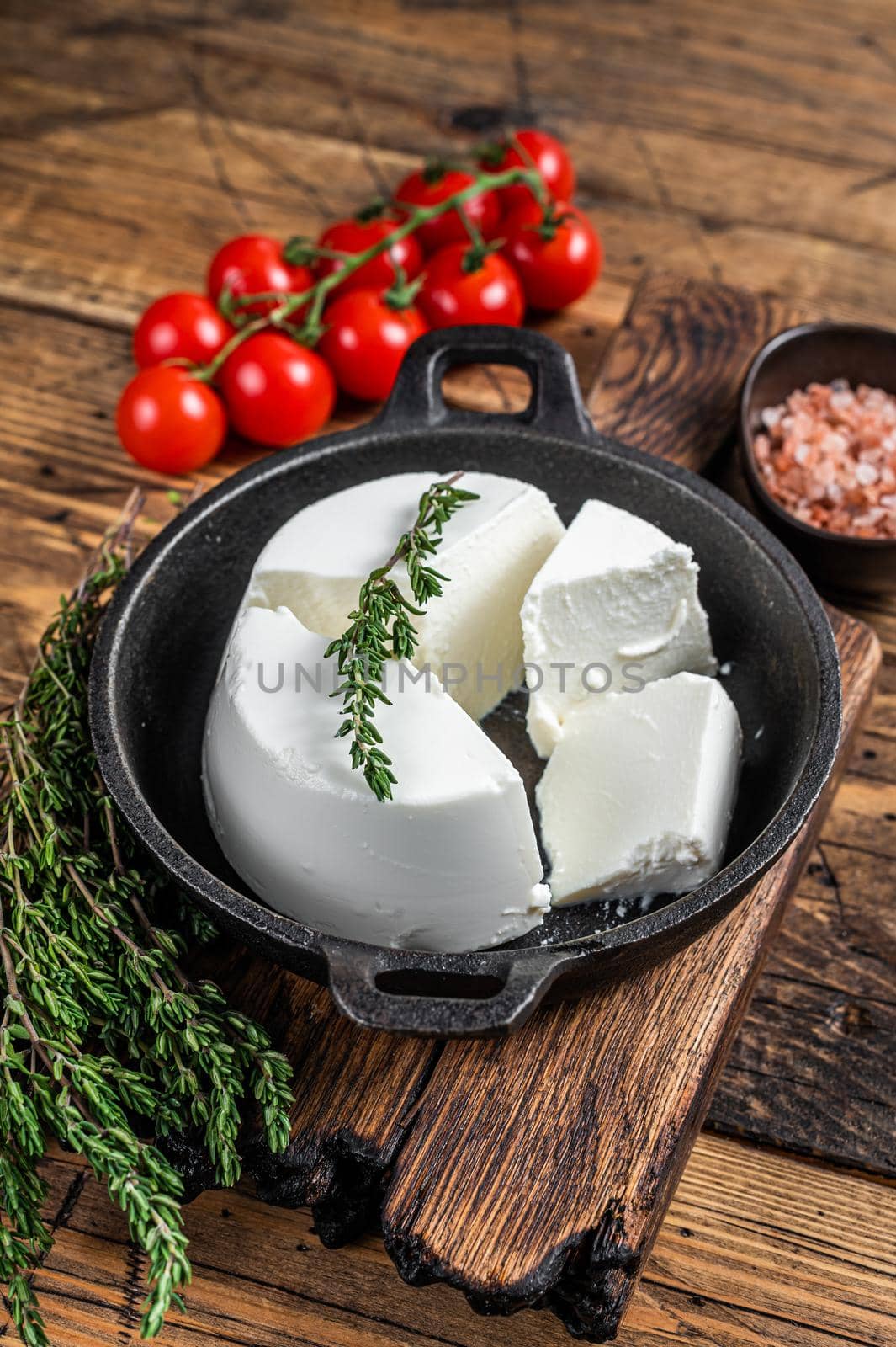 Fresh Ricotta cream Cheese in a pan with basil and tomato. wooden background. Top view by Composter