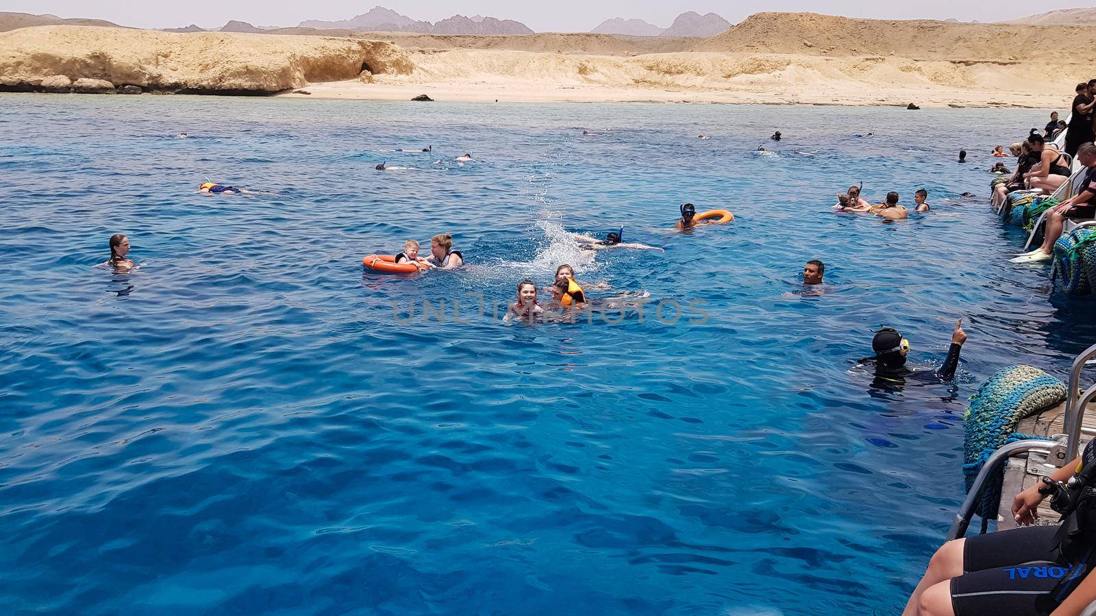 Egypt, Sharm El Sheikh - September 20, 2019: A group of tourists diving with a mask and snorkel are looking at the beautiful and colorful sea fish and coral reef in the Red Sea near the ship