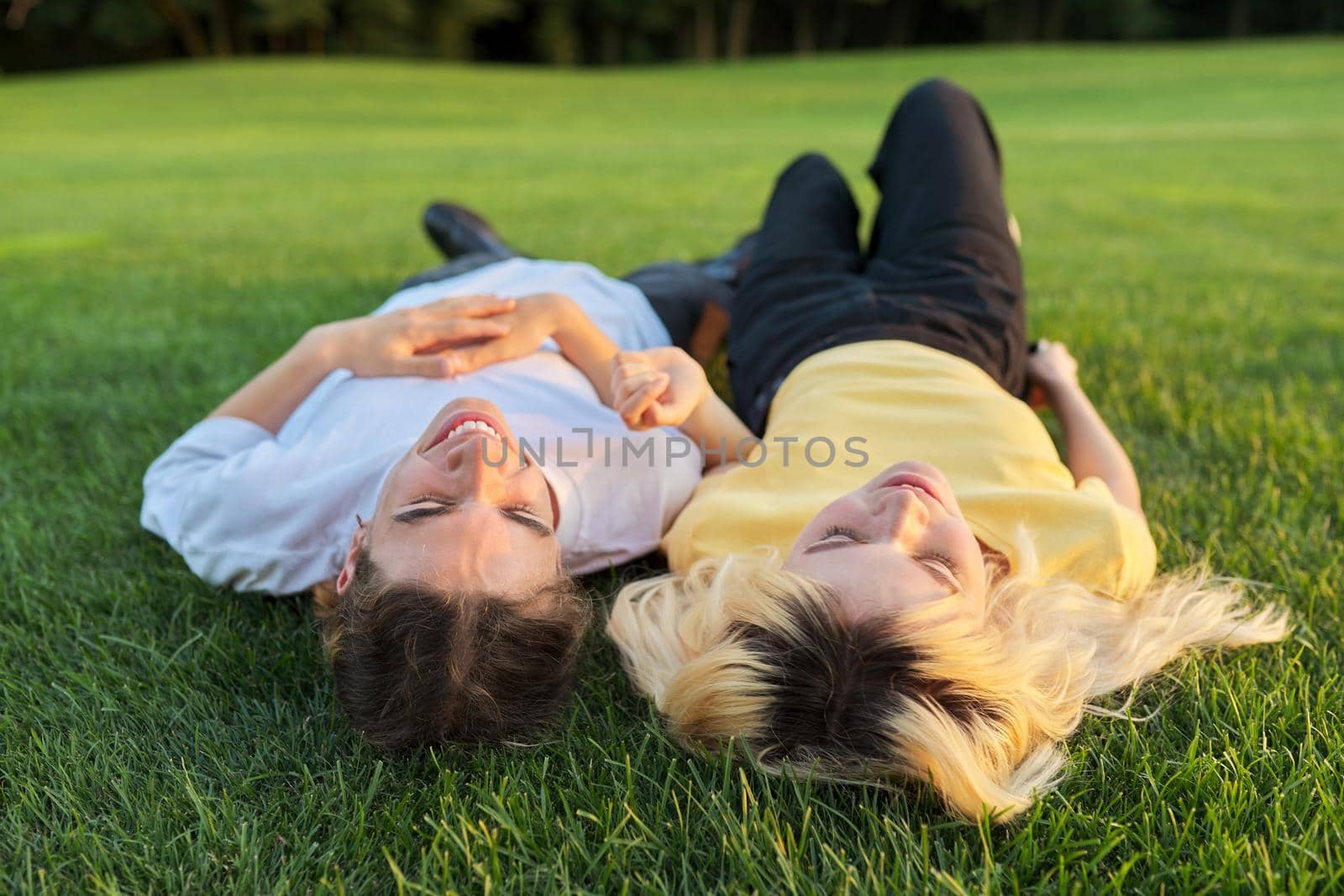 Happy couple of teenagers on green grass by VH-studio