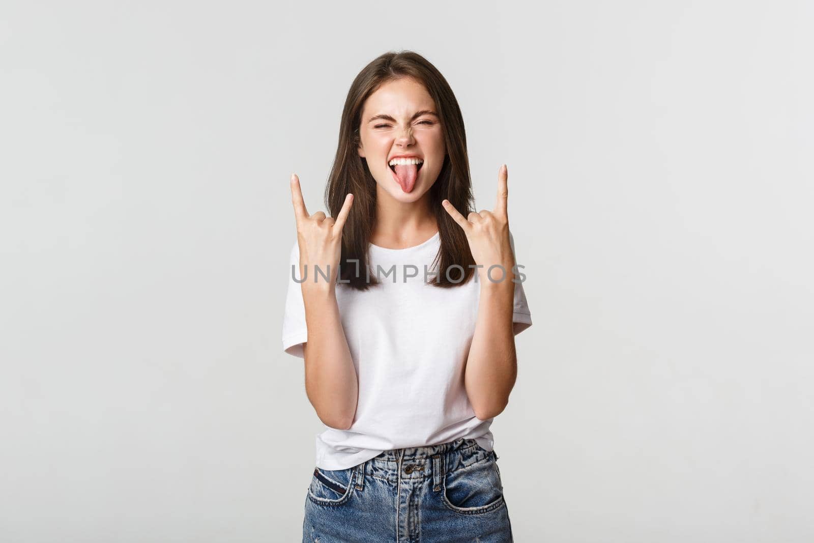 Joyful good-looking girl showing rock-on gesture and enjoying concert.