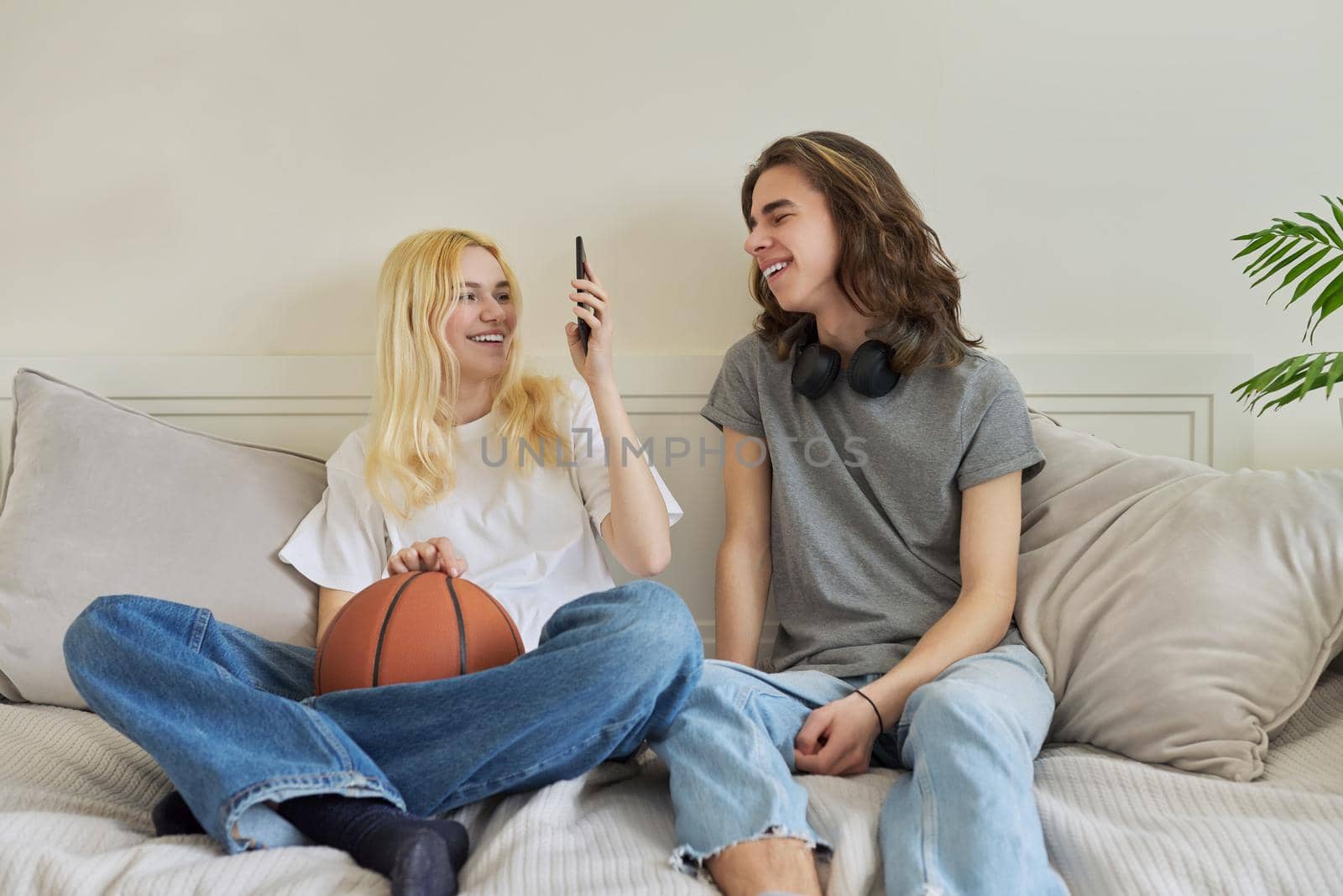 Happy laughing hipster teenagers male and female having fun using smartphone by VH-studio