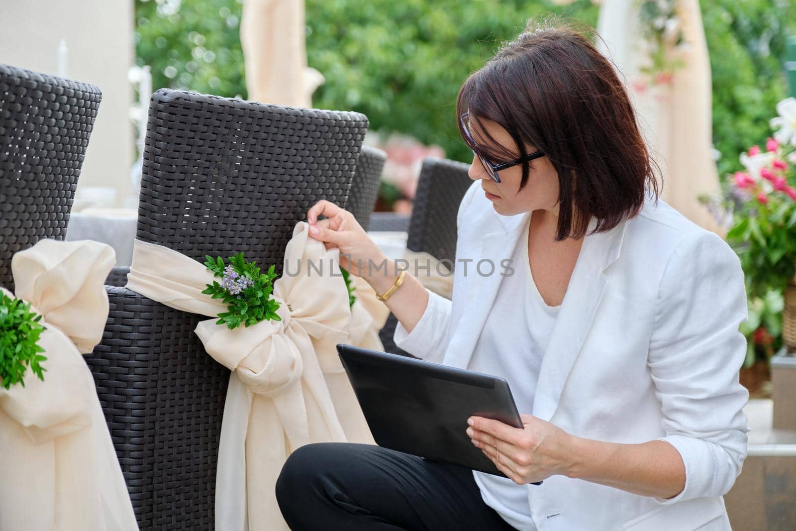 Woman professional decorator with digital tablet working outdoors decorating ceremony by VH-studio