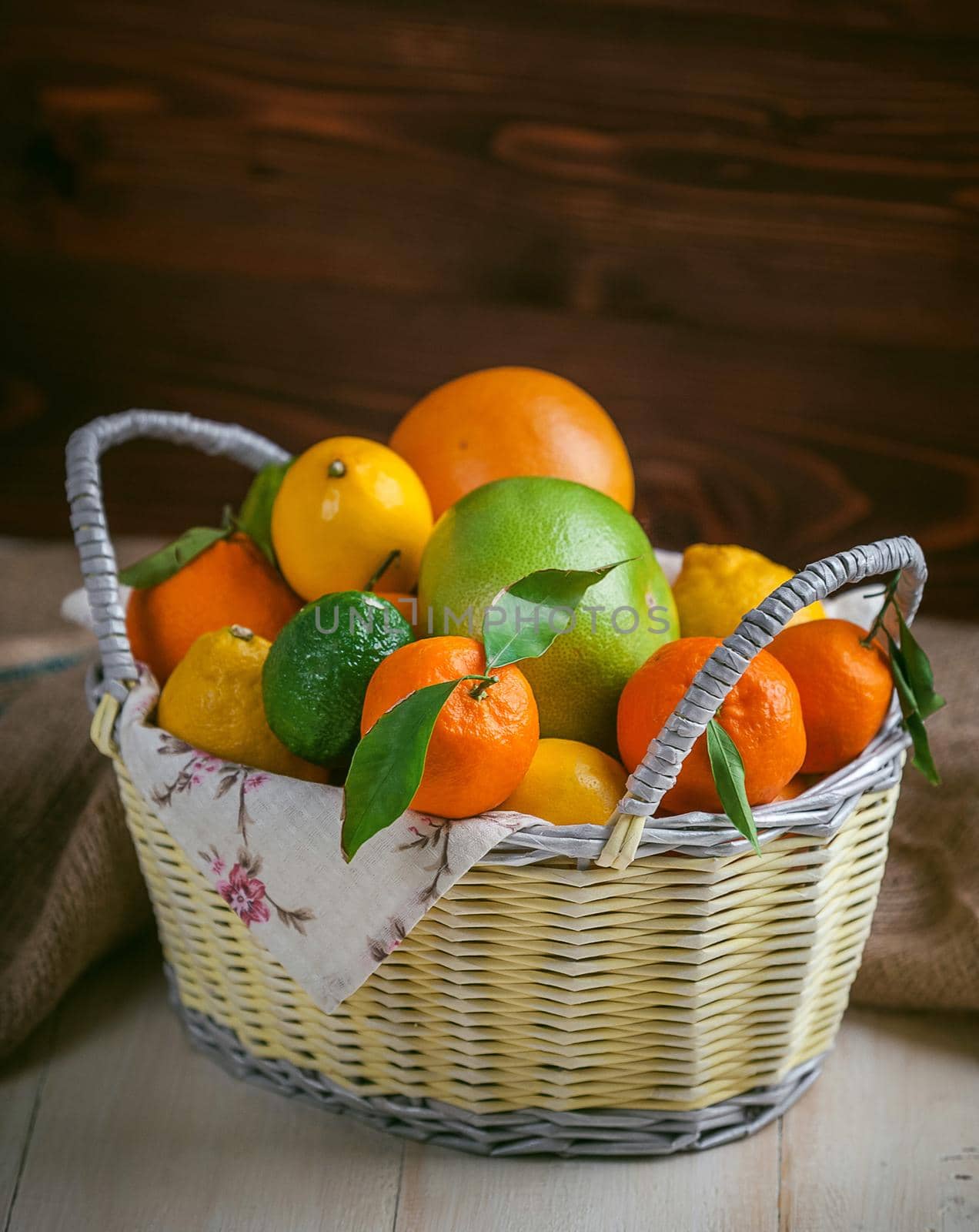 citrus fruits in a wicker basket on a wooden background