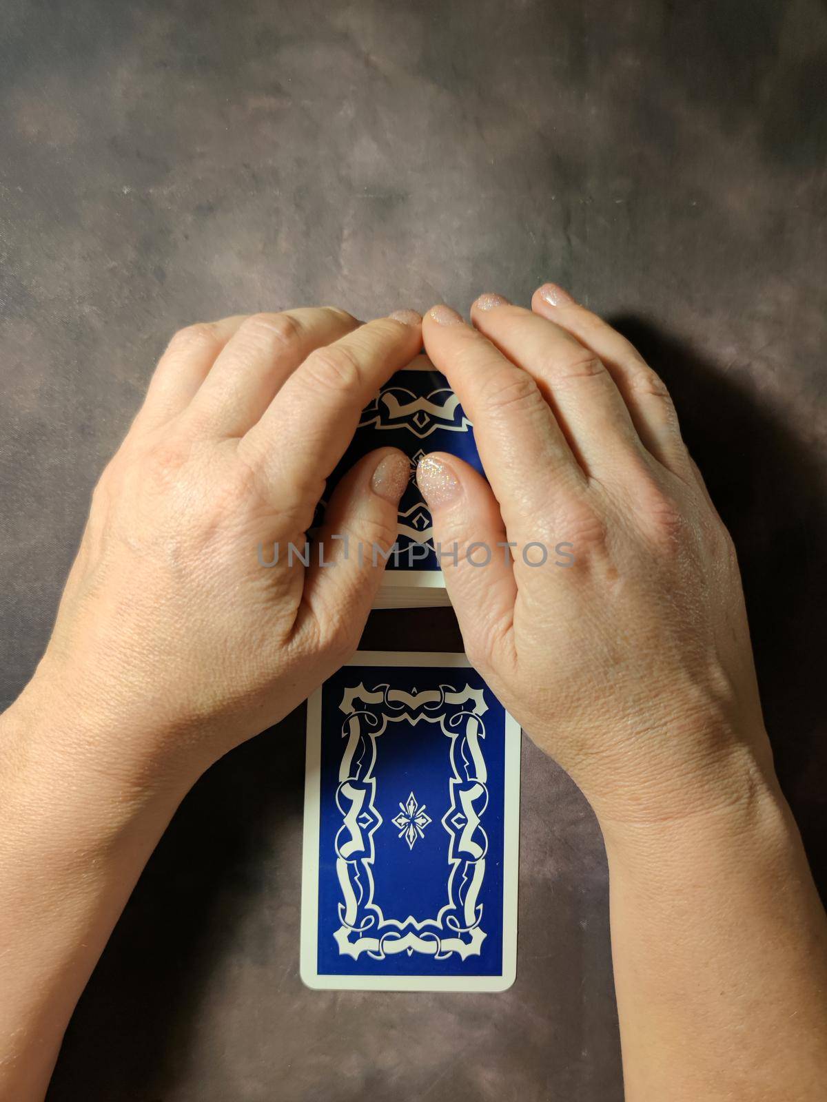 female hands on deck of tarot cards on dark vintage background, view from above