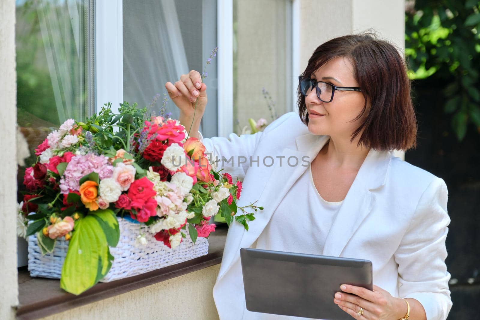 Organization of weddings, parties, event decoration. Business woman professional decorator florist with digital tablet working outdoors decorating ceremony. Female with flower arrangement