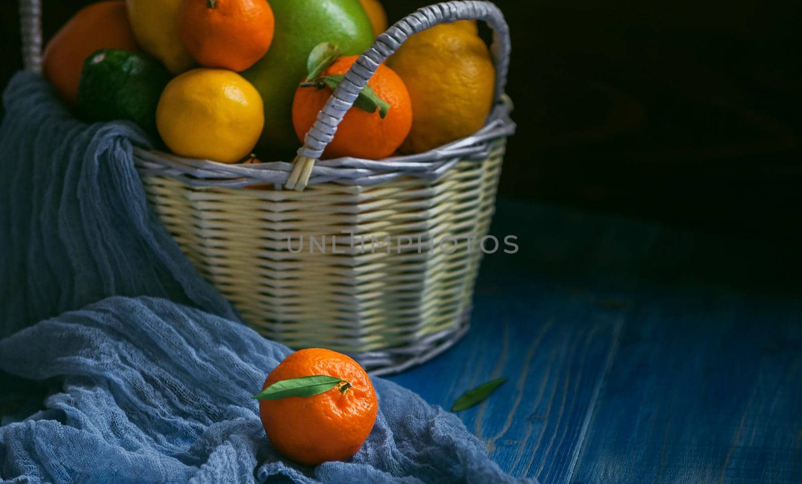 citrus fruits in a wicker basket on a wooden background