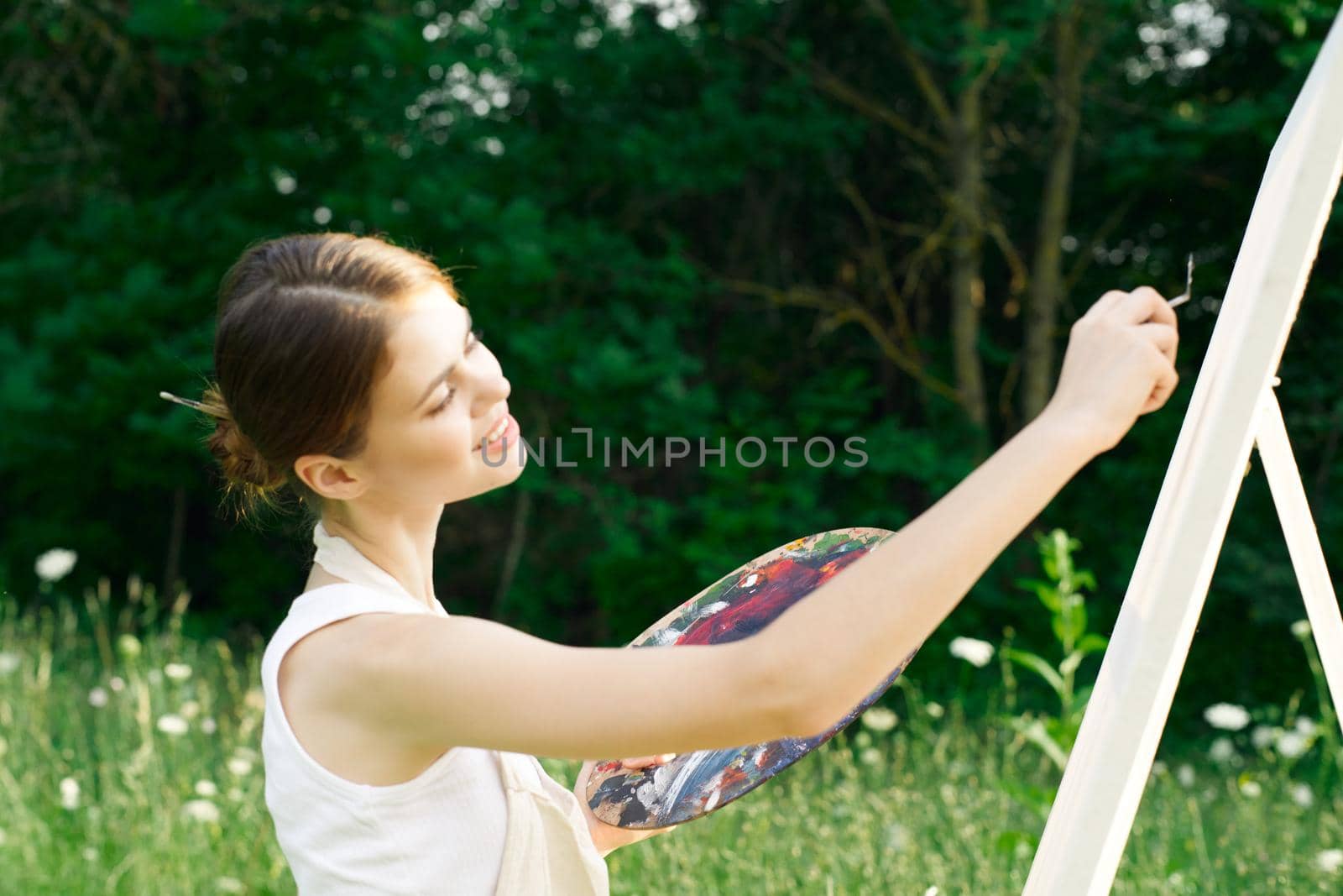 woman artist outdoors with palette of paints paints a picture by Vichizh