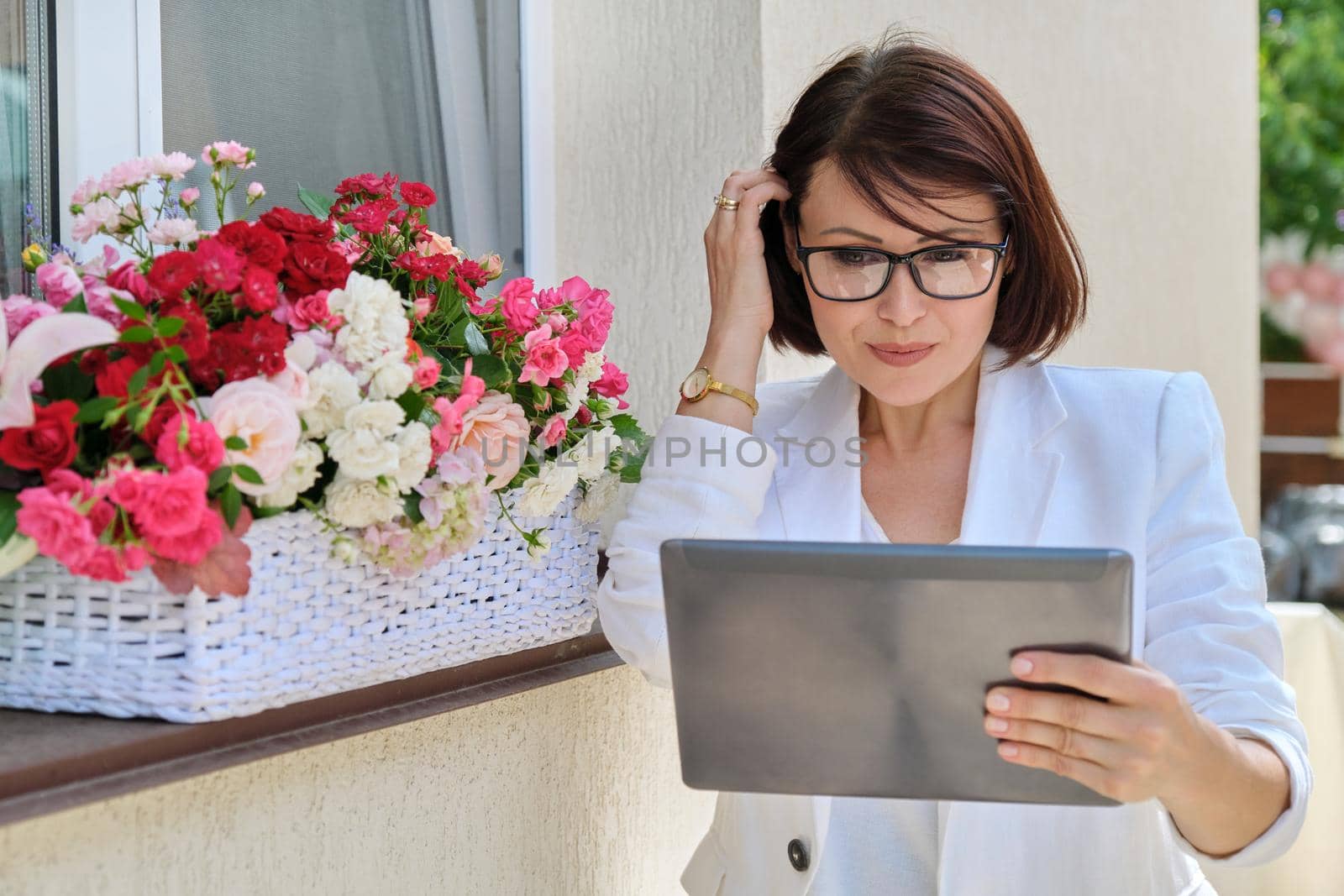 Organization of weddings, parties, event decoration. Business woman professional decorator florist with digital tablet working outdoors decorating ceremony. Female with flower arrangement