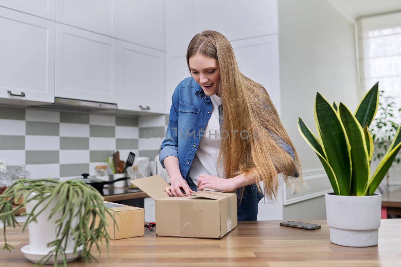 Young happy woman unpacking cardboard boxes, unboxing expected postal parcel by VH-studio