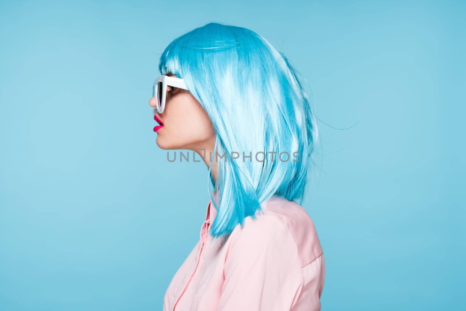 attractive woman in purple wig sunglasses model blue background. High quality photo