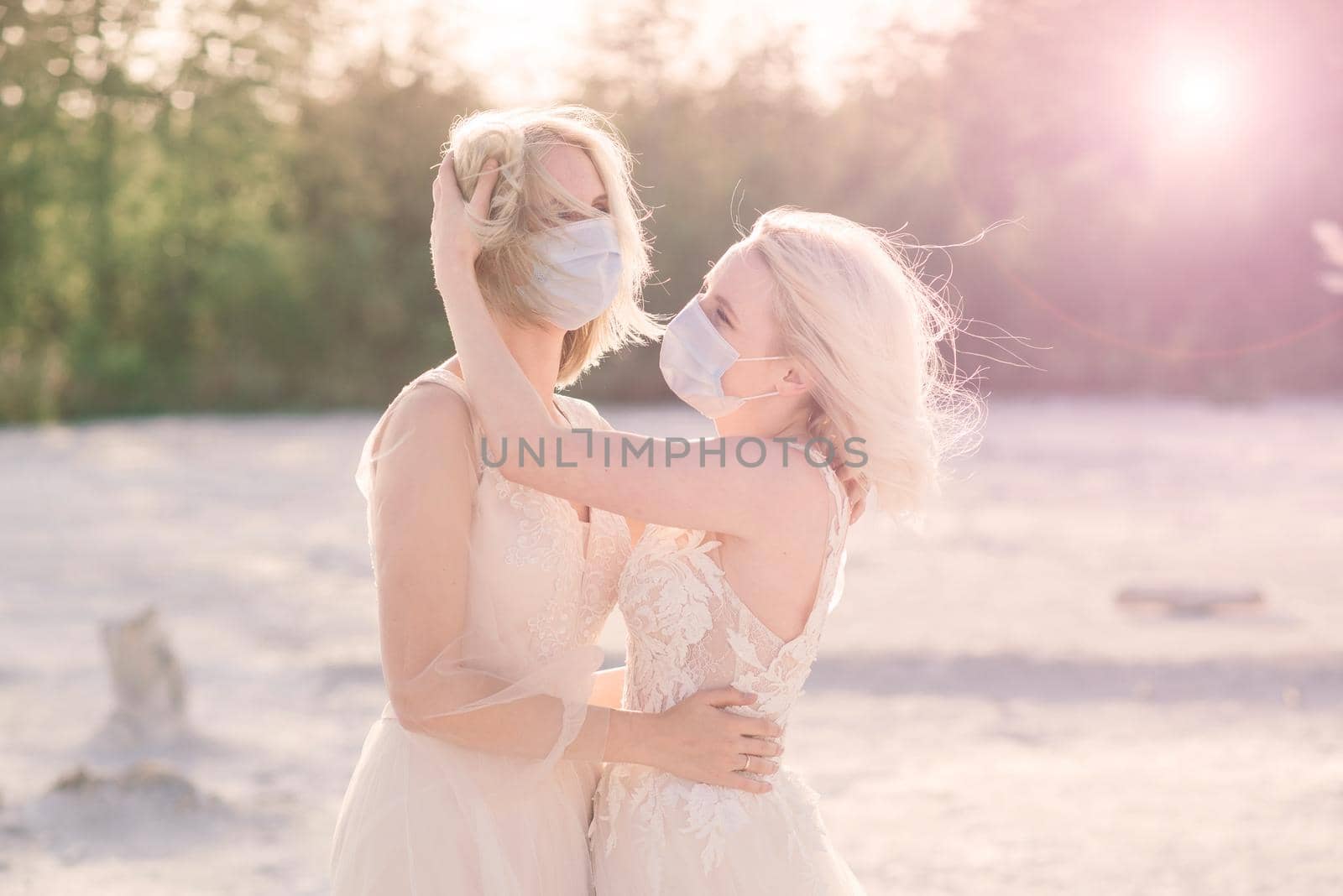 Lesbian couple wedding, wear masks to prevent epidemic COVID-19, on sand background by Zelenin
