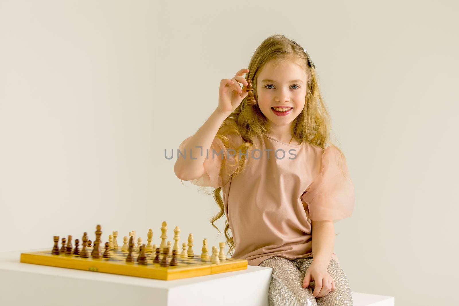 The little girl holds a chess piece in her hand. by kolesnikov_studio