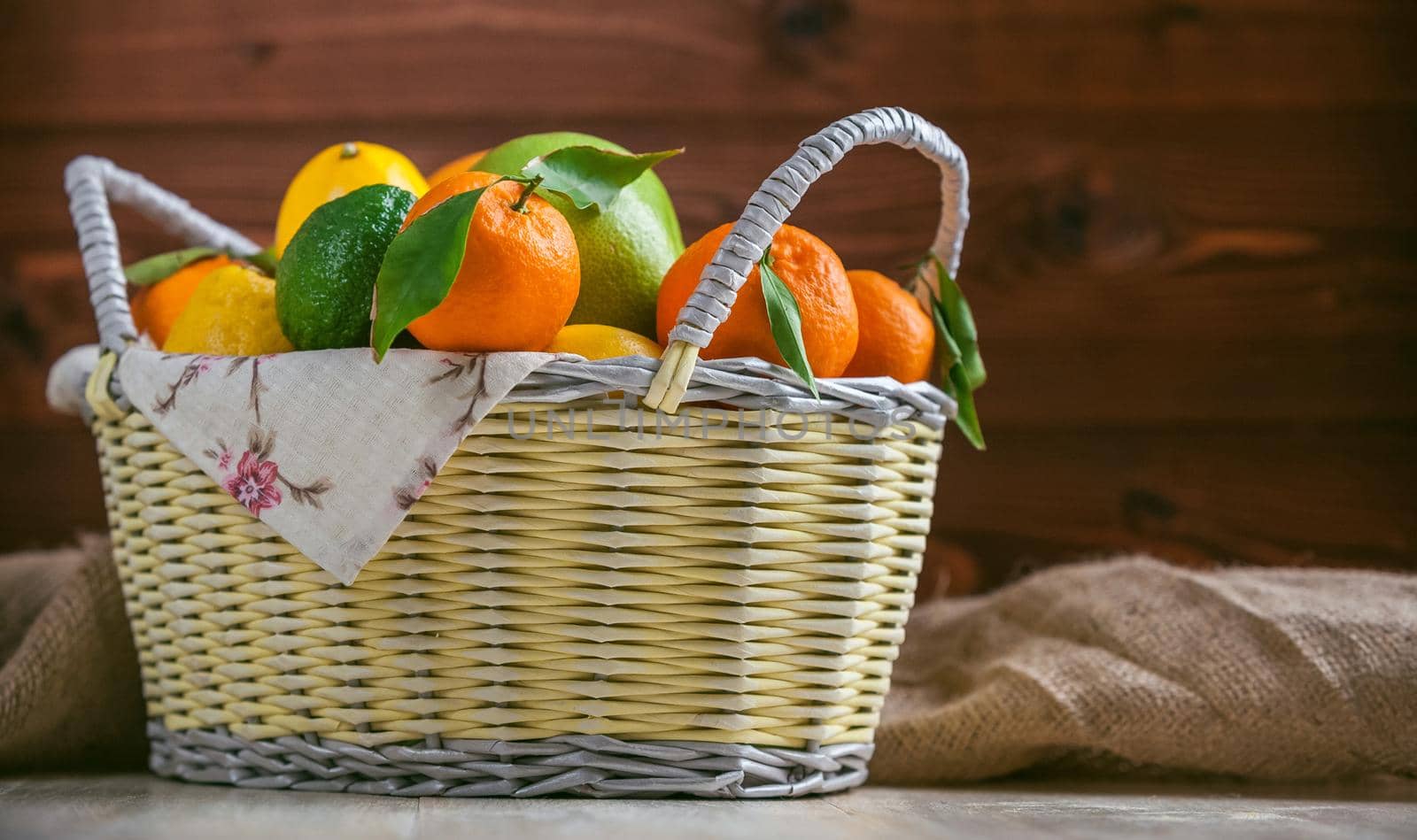 citrus fruits in a wicker basket on a wooden background by vvmich