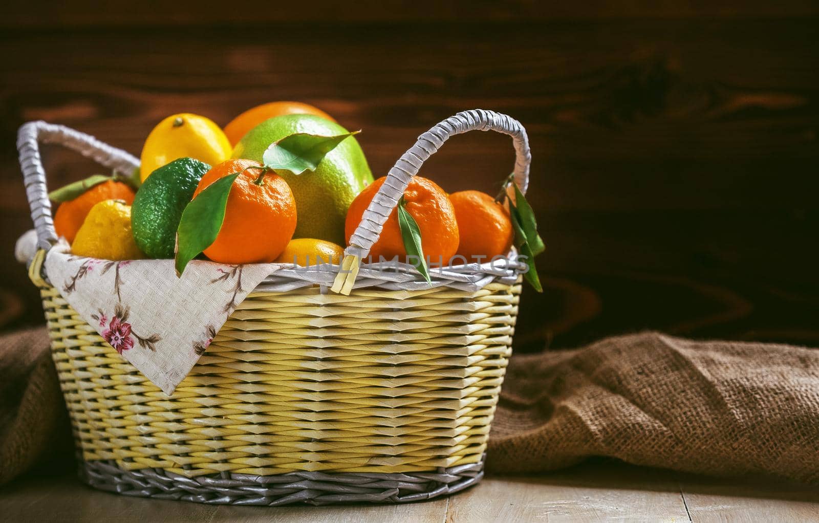 citrus fruits in a wicker basket on a wooden background